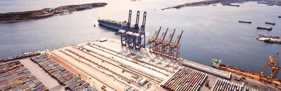 Bird's eye view of a ship coming in to a dock with many shipping containers