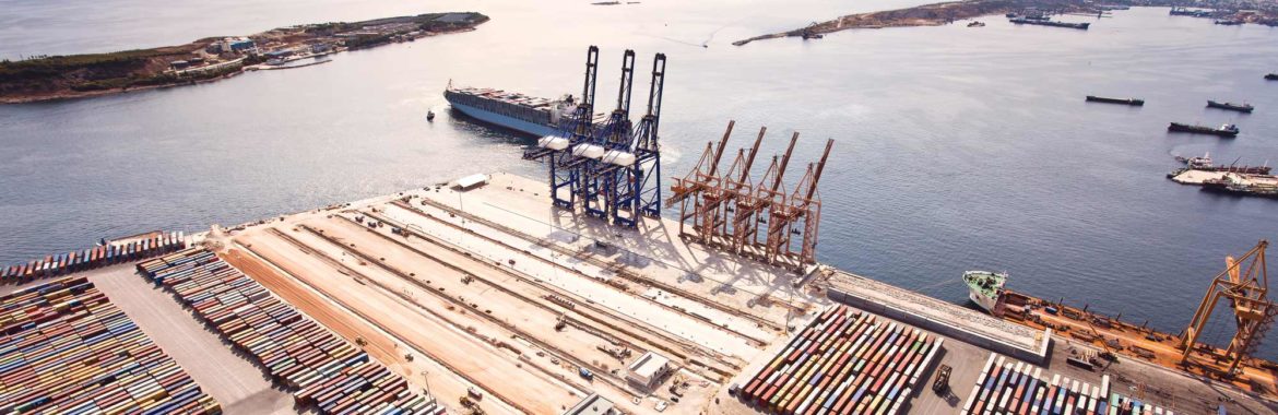 Bird's eye view of a ship coming in to a dock with many shipping containers