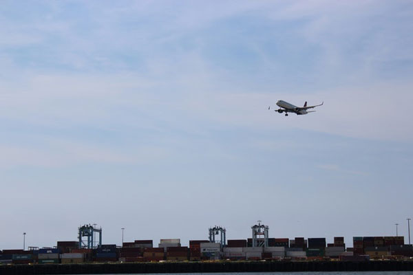 a plane flying over a cargo dock