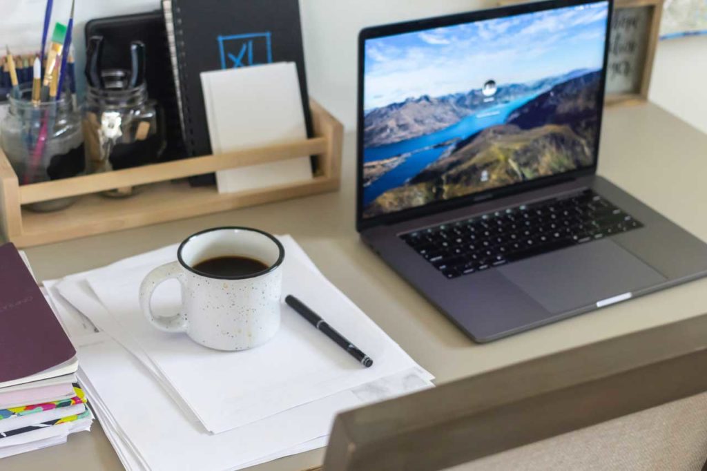 Laptop, coffee, and files in a workspace for virtual events